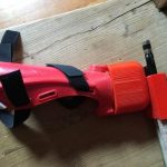 3D printed prosthetic bow holder with bow and velcro for attaching to the arm.